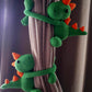 pair of green dino tie backs with orange spikes